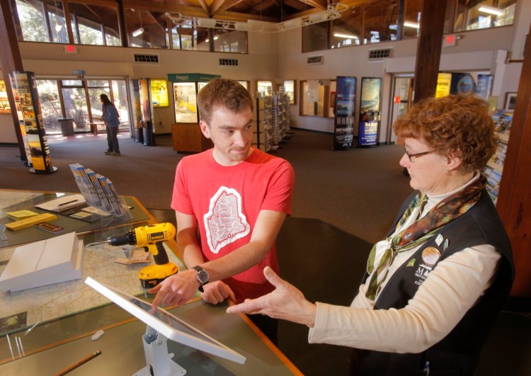 Nate Wildes of Live + Work in Maine explains the operation of an iPad kiosk to Marcia Peverly, manager of the Maine State Visitor Information Center in Kittery, in 2016.   Live + Work is partnering with Educate Maine in an effort to keep college graduates in Maine.