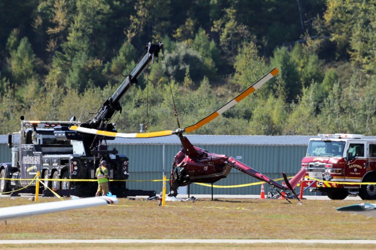 Emergency crews use a tow cable to turn a crashed helicopter upright on Saturday at Sanford Seacoast Regional Airport.