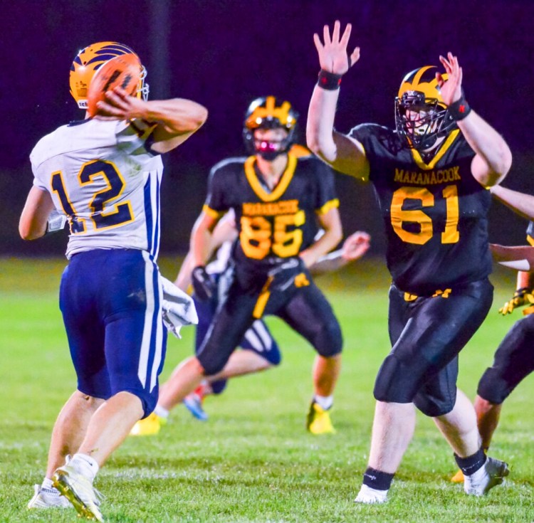Boothbay quarterback Hunter Crocker, left, passes under pressure from Maranacook's Ashael Plum during a game at the Ricky Gibson Field of Dreams on earlier this season in Readfield. 