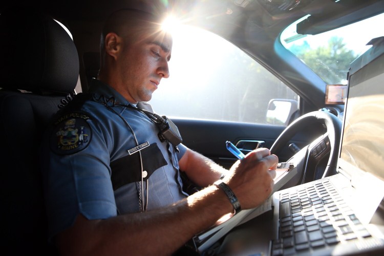 Maine State Trooper Pat Flanagan writes a ticket for a truck driver who was following Flanagan's unmarked cruiser too closely on Interstate 95 on Thursday during a distracted driver detail. 