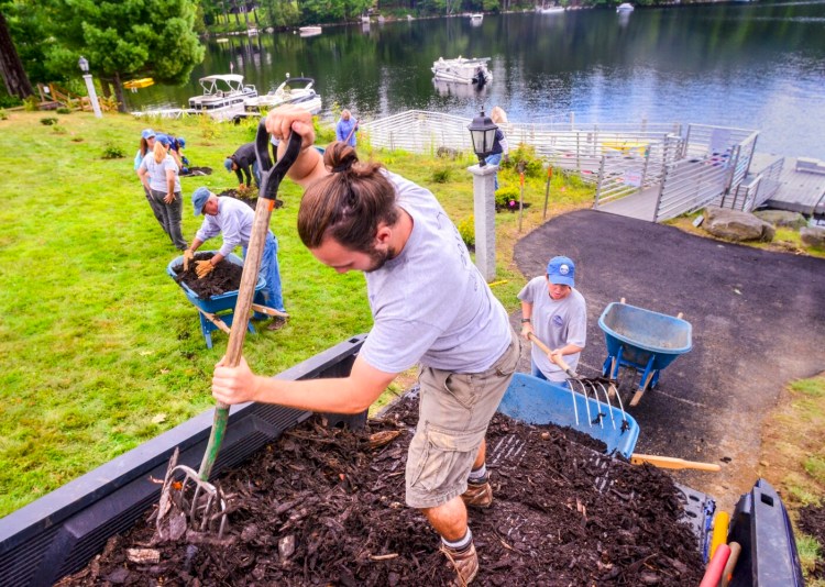 Jacob Violette, center, scoops erosion control mulch from a pickup truck on Tuesday at the waterfront area of Travis Mills Foundation retreat on Long Pond in Rome. 