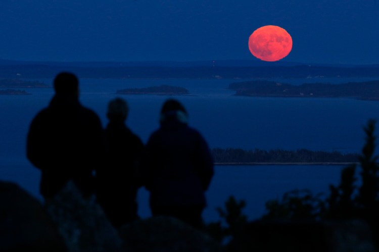 Jack and Kathy Duepree, of Camden, left and center, and their friend Betsy Starman, of Naples, Fla., watch the nearly-full harvest moon rise over Penobscot Bay on Sept. 13 from the summit of Mt. Battie in Camden. Fall is upon us and southern Maine had its first widespread frost on Thursday. 