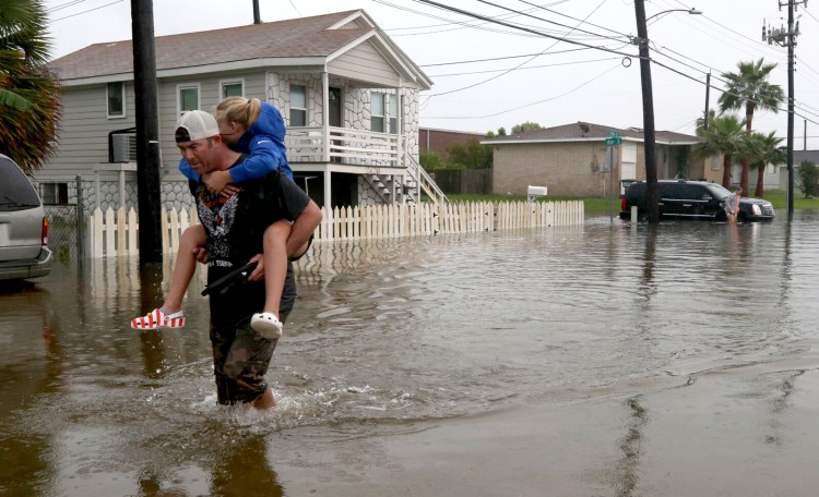 Terry Spencer carries his daughter, Trinity, through high water on 59th Street  in Galveston, Texas, on Wednesday as heavy rain from Tropical Depression Imelda caused street flooding on the island. 
