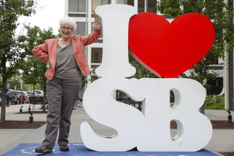Anne Montgomery, mother of Democratic presidential candidate South Bend Mayor Pete Buttigieg, poses on an "I Love South Bend" statue outside his campaign office in South Bend on Wednesday. 