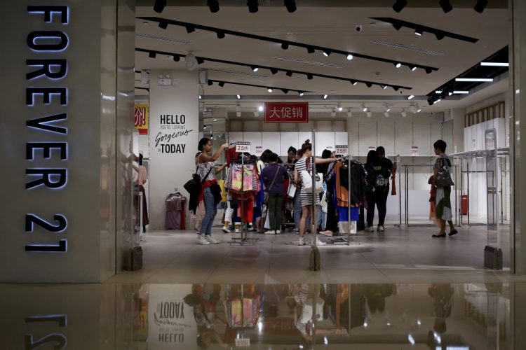 Women select clothing at a Forever 21 store in Beijing, China, last spring. The retailer announced Sunday that it has filed for Chapter 11 bankruptcy protection. Andy Wong/Associated Press