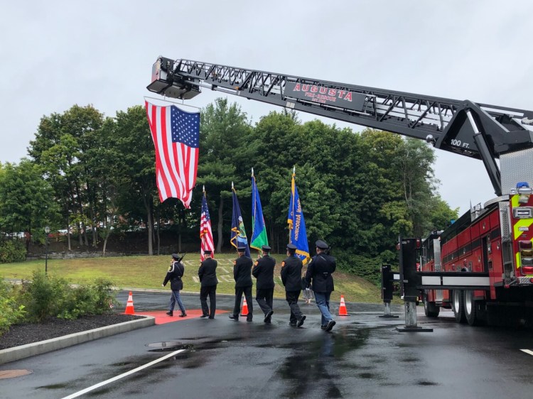A color guard marches under an American flag suspended from a ladder truck at Augusta's Hartford Station following a short ceremony Wednesday remembering those who were lost during the Sept. 11, 2001 attacks.
