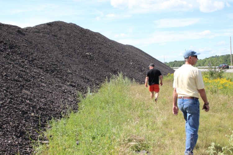 Benjamin Redmond, left, and code enforcement officer Robert Forrest inspect the growing pile of asphalt in Durham. 