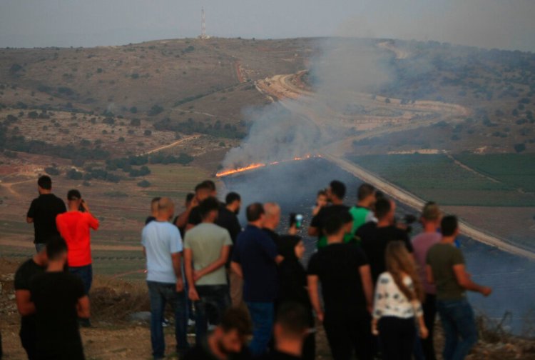 Lebanese journalists and villagers watch as Israeli army shells cause fires on the southern Lebanese border village of Maroun Al-Ras on Sunday. 