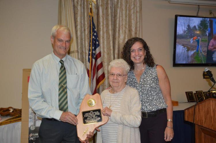 Elaine Mann, center, with MDIFW Commissioner Judy Camuso, right, and MDIFW Deputy Commissioner Tim Peabody, left, as she accepts a Lifetime Achievement Award on behalf of her late husband. 
