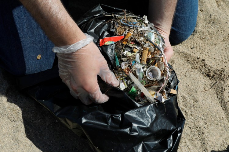 Nathan Goldberg, outreach affiliate with Alliance for the Great Lakes, holds a bag with garbage that was collected during a cleanup event in Chicago on August 22. In July, Illinois Gov. J.B. Pritzker signed into law a bill directing the state Environmental Protection Agency to examine the role of microplastics in drinking water.