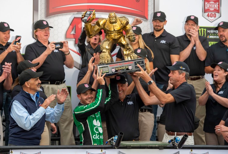 Jason Minto/Associated Press
Kyle Larson receives help Sunday in holding up the championship trophy he earned by winning at Dover. Far more important than the trophy was a berth in the final eight of the NASCAR Cup playoffs.