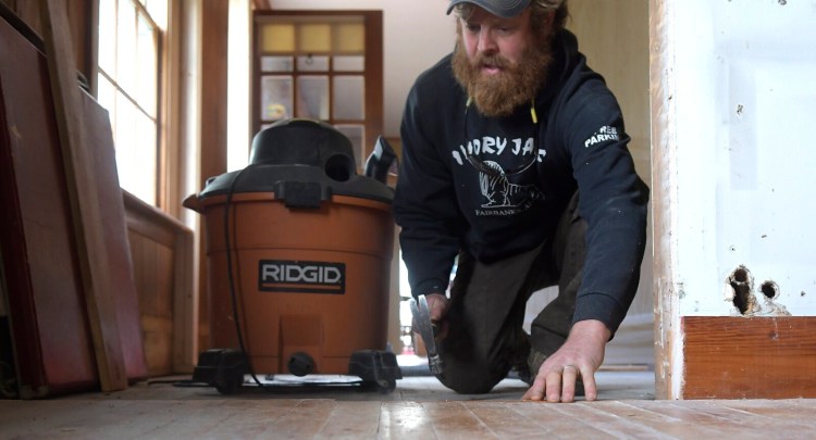 Chase Morrill, one of the stars of the "Maine Cabin Masters" reality television program, pounds a nail in 2019 into the floor of the farmhouse his family bought in Manchester. Kennebec Property Services LLC, also known as the "Maine Cabin Masters," reached a settlement recently with the U.S. Environmental Protection Agency over lead paint safety violations.