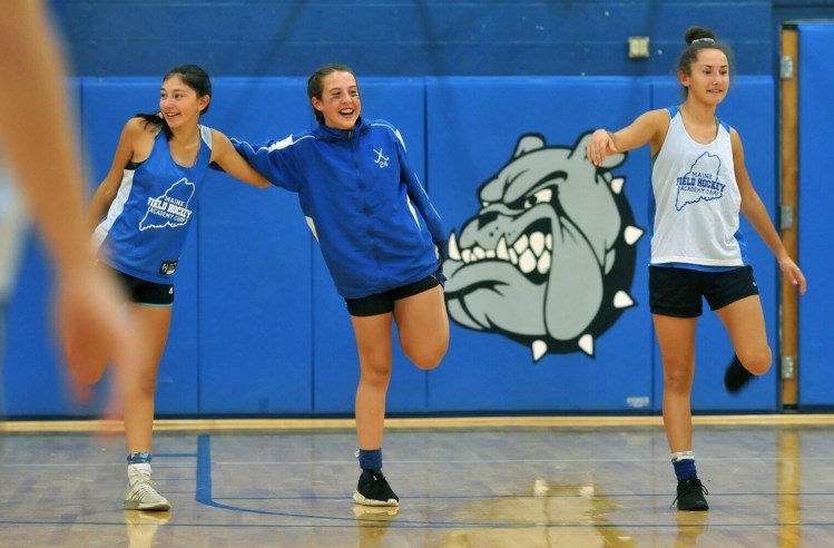 Lawrence field hockey players, from left, Holly Bolduc, and MaKenzie and Hope Bouchard, stretch at the start of practice Monday in Fairfield. 