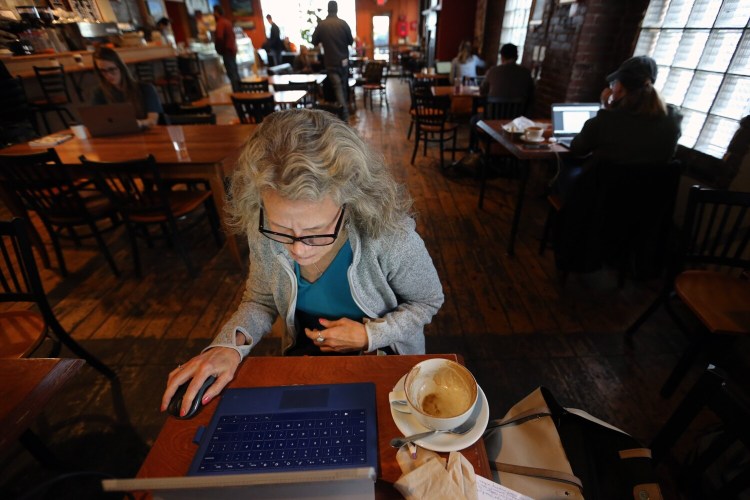 Marge Stockford of Portland works on her laptop Friday at Arabica Coffee after finishing a cup of cappuccino. Stockford chose the spot for its Internet connection because she had been without power since Thursday's early-morning nor'easter.