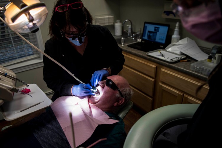 Dr. Demi Kouzounas, removes and replaces a filling and fixes a cracked tooth for Bruce Tibbetts of Mount Vernon at a free dental clinic at Northwoods Dental in Skowhegan on Nov. 2, 2018. Tibbetts and his wife both made the trip to Skowhegan. Tibbetts, a state employee for over forty years, has not had dental insurance for him and his wife since retiring. Northwoods is taking part in this year's Dentists Who Care for Maine program on Friday.