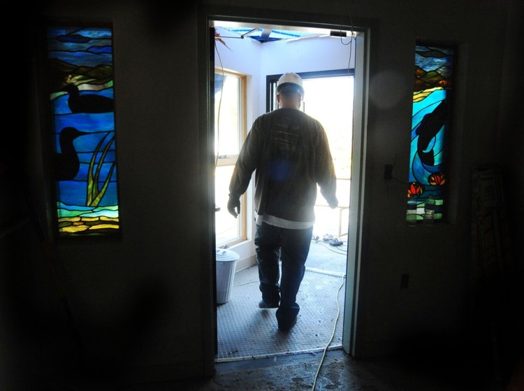 A worker passes through and entryway and into a construction area Tuesday at the Madison Health Center in Madison. The work is part of an interior and exterior enhancement project at the 8 Main St. facility. 