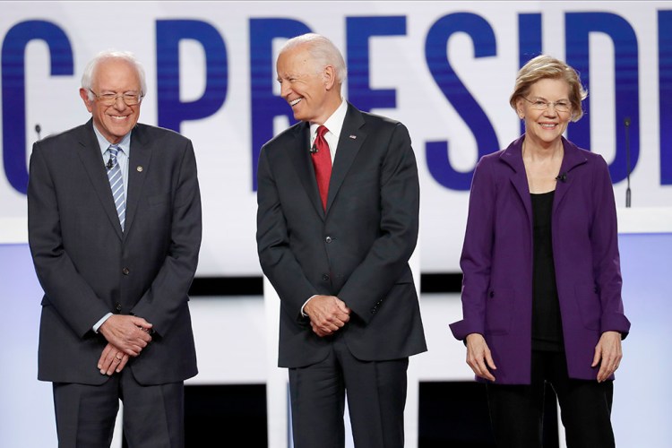 Leading Democratic presidential candidates Bernie Sanders, Joe Biden and Elizabeth Warren stand on stage before Thursday's Democratic presidential primary debate at Otterbein University in Westerville, Ohio.
