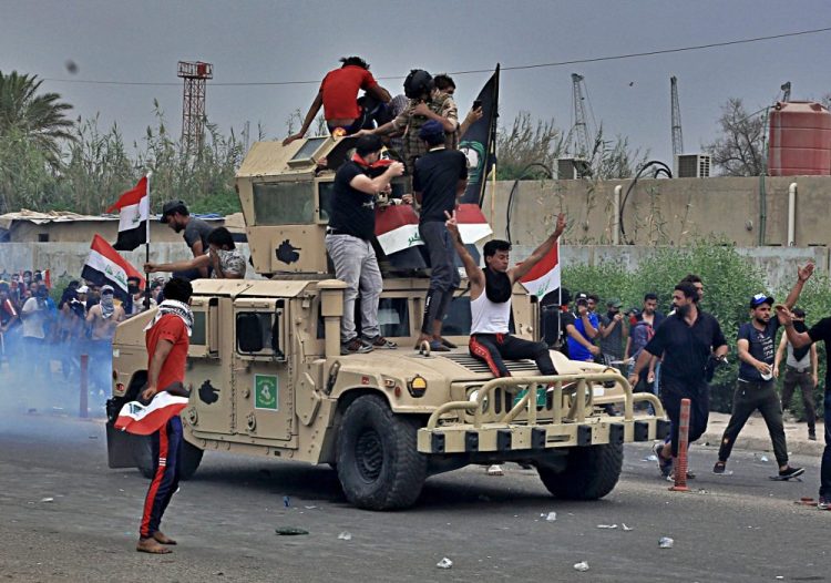 Protesters ride an Iraqi army armored vehicle during a demonstration in Basra on Friday.

