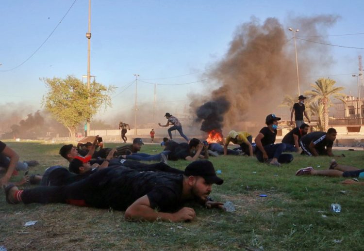 Anti-government protesters take cover while Iraq security forces fire during a demonstration in Baghdad, Iraq on Friday. Thousands have taken to the streets of several areas in oil-rich Iraq to protest against corruption, lack of jobs and poor services.