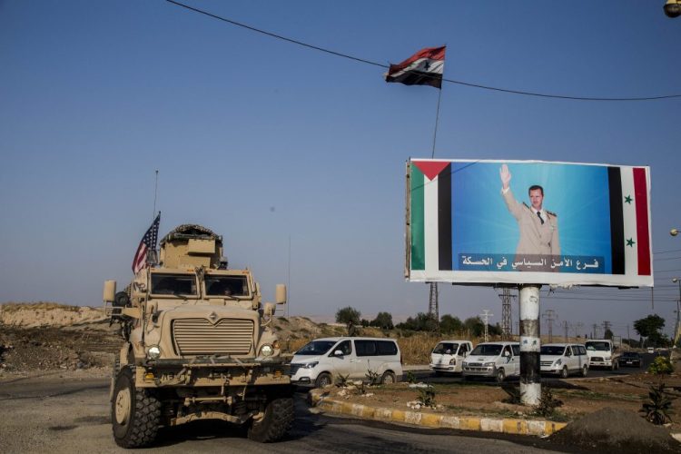 A U.S. military convoy drives through the town of Qamishli, north Syria, past a poster showing Syrian President Bashar Aassad on Saturday.

Baderkhan Ahmad/Associated Press