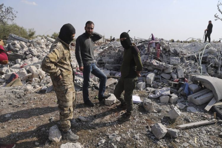 People look at a destroyed houses near the village of Barisha, in Idlib province, Syria, on Sunday after an operation by the U.S. military which targeted Abu Bakr al-Baghdadi, the shadowy leader of the Islamic State group. 