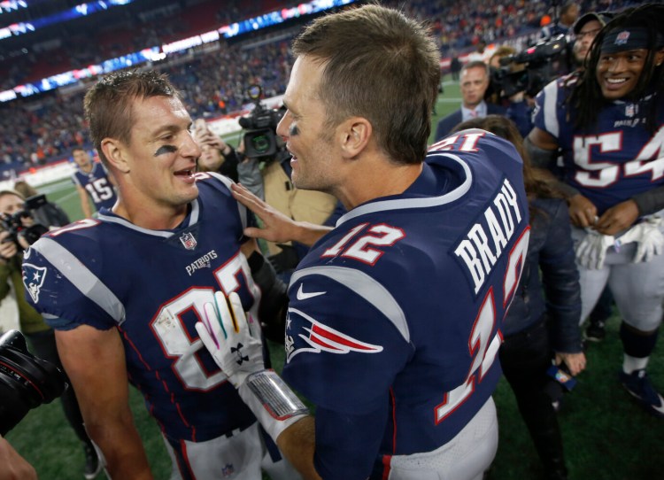 Former New England Patriots tight end Rob Gronkowski, left, and quarterback Tom Brady speak at midfield after beating the Kansas City Chiefs last October in Foxborough, Mass. The Patriots have reportedly agreed to trade Gronkowski, who retired after the 2018 season, to Tampa Bay so he can reunite with Brady.