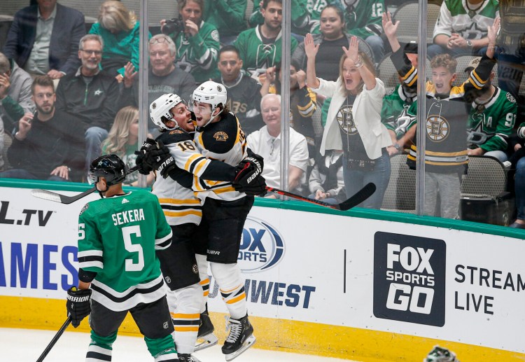 Dallas Stars defenseman Andrej Sekera skates past as Boston Bruins forward Brett Ritchie, 18, is congratulated by forward Jake DeBrusk after scoring a goal during the first period of the Bruins' 2-1 win Thursday in Dallas. 