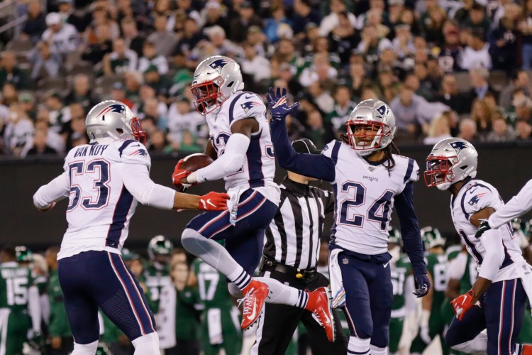 New England Patriots free safety Devin McCourty celebrates with teammates Kyle Van Noy, 53, and Stephon Gilmore after intercepting a pass during the Patriots' win over the Jets on Monday in East Rutherford, N.J.