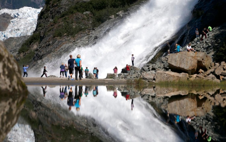 Tourist at the Mendenhall Glacier in the Tongass National Forest are reflected in a pool of water as they make their way to Nuggett Falls in 2013 in Juneau, Alaska. The Trump administration Tuesday proposed allowing logging on more than half of the 16.7 million-acre Tongass, the largest intact temperate rainforest in North America.