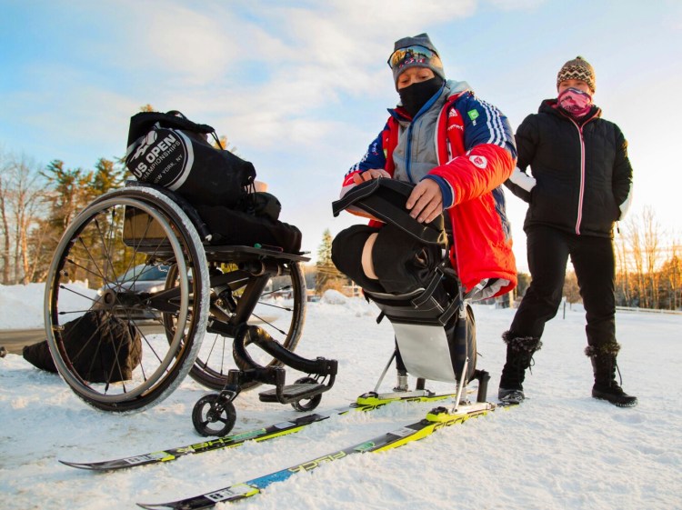 Paralympic hopeful Eric Frazier straps into his adaptive cross country skis, as Kristina Sebastianski the director of the Pineland Farms' Veterans Adaptive Sports & Training, keeps him from sliding. Frazier, a former Marine, was training for the Nordic skiing event at the Outdoor Center at Pineland Farms in New Gloucester on Dec. 28, 2017. 
