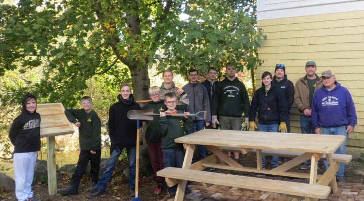 The brick pad, the picnic table and sign placard near the Outlet Stream are part of Ben Legasse's Eagle Scout Project. From left are Kameron Rossignol, Kasen Kelley, Remy Pettengill, Ayden Newell and Caleb Knock. Back from left are Ben Lagasse, Aiden Pettengill, Hunter Praul, Kaiden Kelley, Michael Boostedt, Leaders Derek Rossignol, Darryl Praul and Ron Emery. Also helping, though not in photo, were Leaders Lee Pettengill and parents Keith Lagasse, Jonathan Knock and Grange member Bernie Welch.