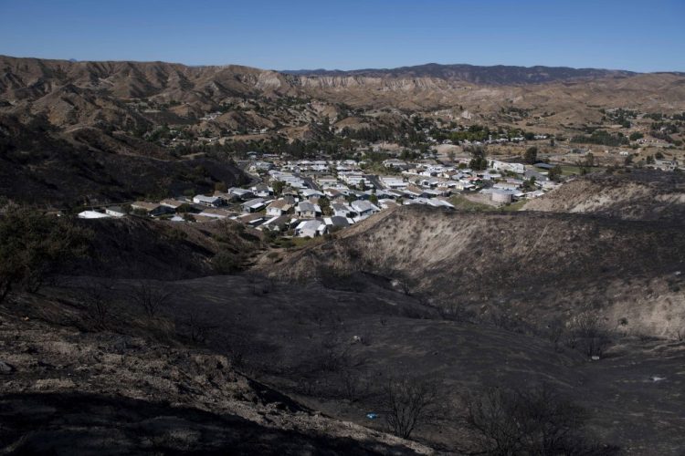 A mobile home community sits between charred hillsides from the Tick Fire on Thursday in Santa Clarita, Calif. 