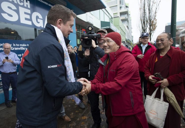 A Tibetan monk shakes hands with Conservative leader Andrew Scheer outside a campaign office in Vancouver, British Columbia, Sunday, Oct. 20, 2019. 