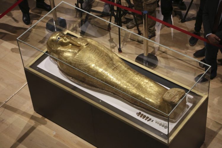 Journalists gather around the golden coffin that once held the mummy of Nedjemankh, a priest in the Ptolemaic Period some 2,000 years ago, at the National Museum of Egyptian Civilization, in Old Cairo, Egypt, Tuesday, Oct. 1, 2019. 
