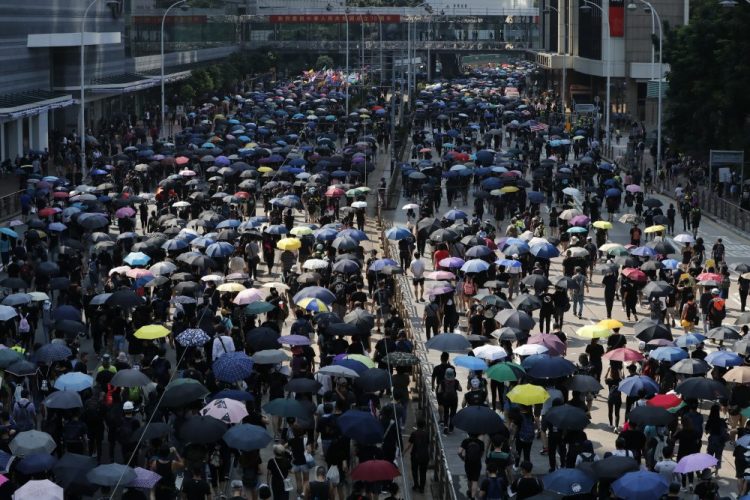 Anti-government protesters holding umbrellas march past police headquarters in Hong Kong, Tuesday, Oct. 1, 2019. 