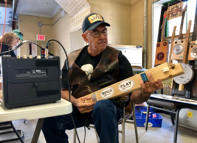 Marty Tauber of Maine Made CBGs plays a diddley bow Sunday at Hallowell’s third annual Maine Luthiers Showcase. He made the instrument out of a board.