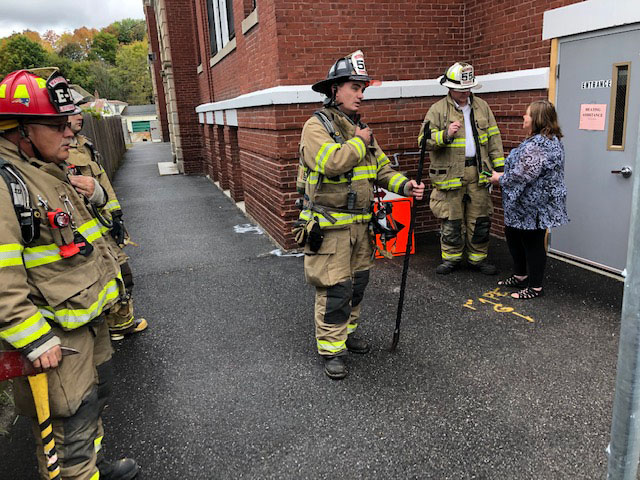 Waterville Fire Chief Shawn Esler, at right in white helmet, talks to KVCAP executive assistant Wanda Steward before firefighters left the scene Friday. Firefighters were called to KVCAP to investigate a possible gas leak.
