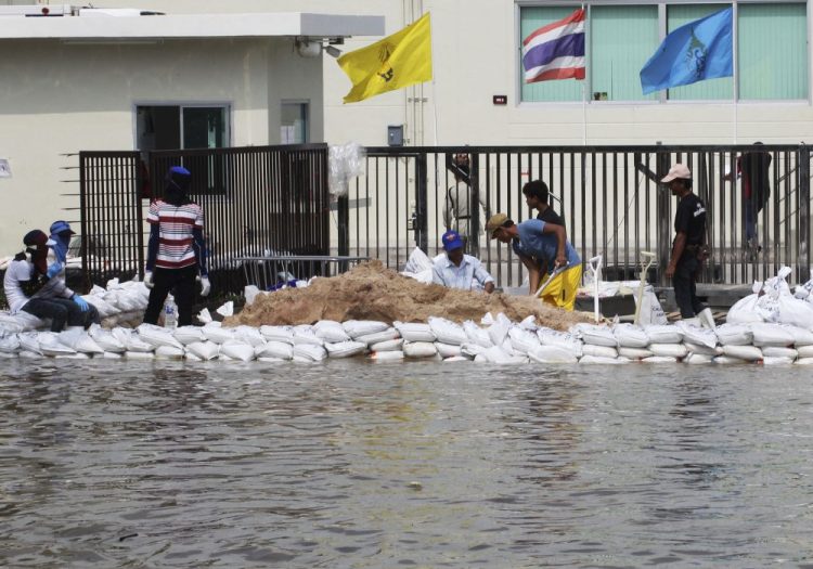 FILE - In this Oct. 9, 2013, file photo, Workers build a water barrier with sandbags as floodwater threatens their factory at Amata Nakorn industrial estate in Chonburi province, eastern Thailand, in 2013. 