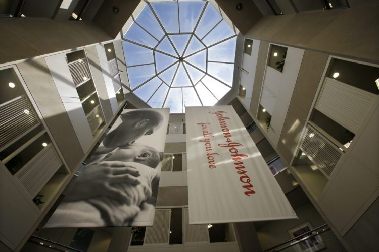 Large banners hang in an atrium at the headquarters of Johnson & Johnson in New Brunswick, N.J. Johnson & Johnson has become the latest company to settle a lawsuit to get out of the first federal trial over the nation's opioids crisis, reaching a deal worth more than $20 million with two Ohio counties, the company announced Tuesday.
