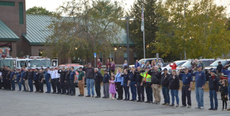 Firefighters salute while others put their hands over their hearts Tuesday evening as they welcome Farmington Fire Rescue Chief Terry Bell home from a Portland hospital more than three weeks after he was critically injured in a deadly propane explosion.