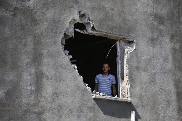 A resident looks out from a hole in a house that was damaged by a mortar fire in the Turkish town of Akcakale on Saturday. President Trump has withdrawn U.S. forces in Syria, saying he wanted to stop getting involved with "endless wars."