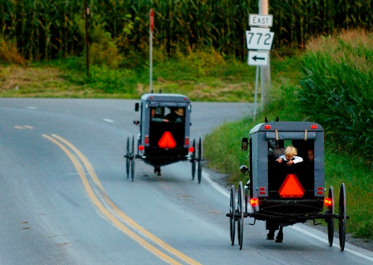 Amish hourse-drawn buggies trot along Pennsylvania  roads in 2003.