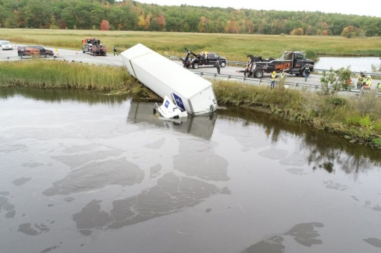 Crews prepare to remove a tractor-trailer truck that crashed into a dike along Route 1 in Woolwich, spilling several gallons of diesel into the water. 