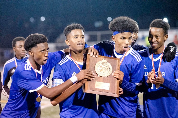 Lewiston High School seniors Suab Nur, left, Moubarek Abdourahman, Bilal Hersi and Abdilahi Abdi celebrate with the Maine Principal's Association trophy after beating Brunswick 3-1 to win the North Regional Championship in bath on Tuesday.
