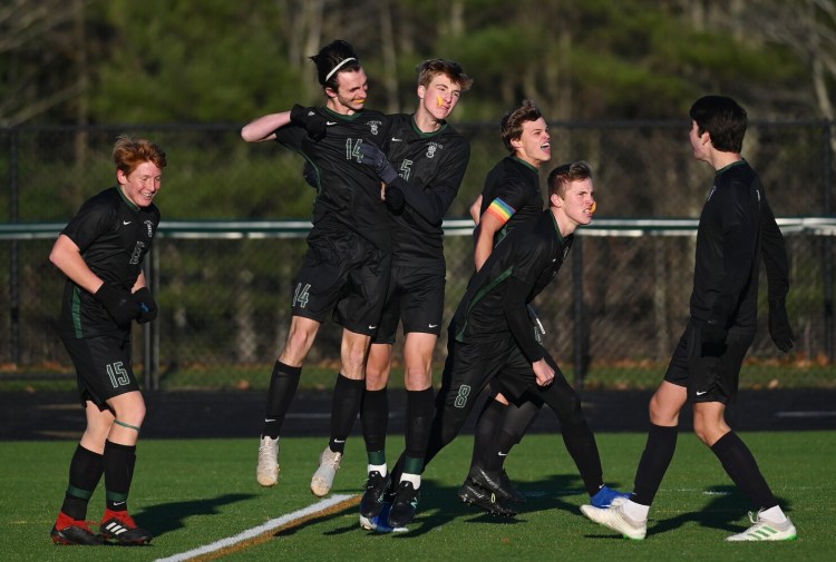 Waynflete's Joey Ansel-Mullen (14) celebrates with teammates, including Harry Millispaugh (5) after scoring the game's first gaol against Mount View in the Class C state championship Saturday in Falmouth.