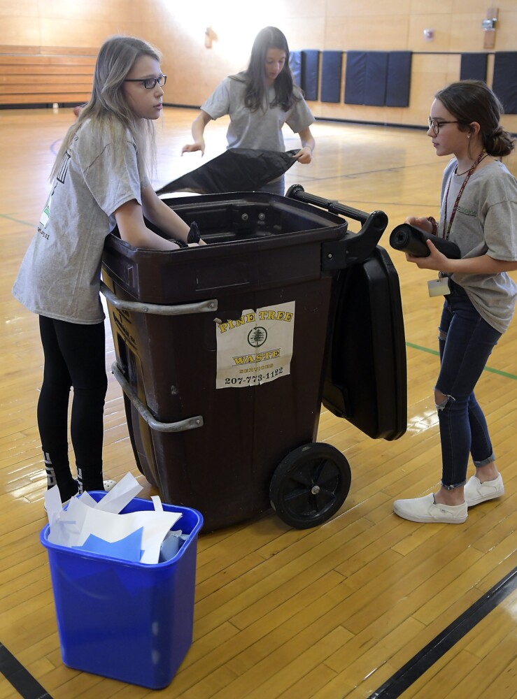 Maranacook Community Middle School students Tilden Tinkham, left, Natalie Mohlar and Mya St. Pierre recycle paper Nov. 25 at the Readfield school's gym. The crew volunteer with the school's Green Team.