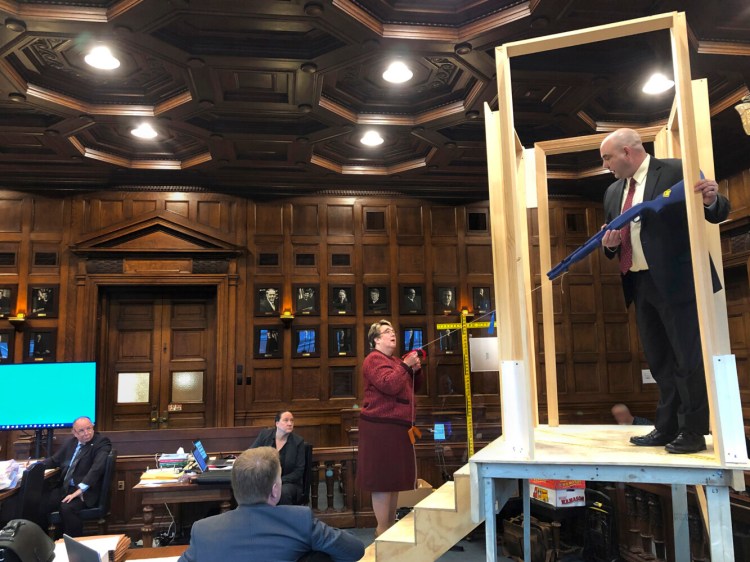 In Cumberland County Superior Court on Monday, Maine State Police Detective Larry Rose holds a mock shotgun while standing at the top of a replica of the stairs in the Windham home where Noah Gaston shot and killed his wife, Alicia Gaston, as she ascended the stairs on the morning of Jan. 14, 2016. Assistant Attorney General Meg Elam holds a string to show the potential path of the shot.