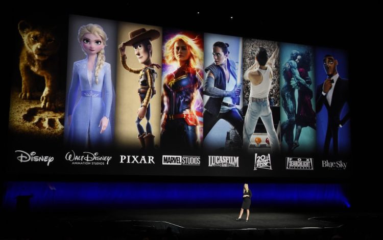 In this April 3, 2019, file photo characters from Disney and Fox movies are displayed behind Cathleen Taff, president of distribution, franchise management, business and audience insight for Walt Disney Studios during the Walt Disney Studios Motion Pictures presentation at CinemaCon 2019, the official convention of the National Association of Theatre Owners (NATO) at Caesars Palace in Las Vegas. On Tuesday, Disney Plus launched its streaming service.