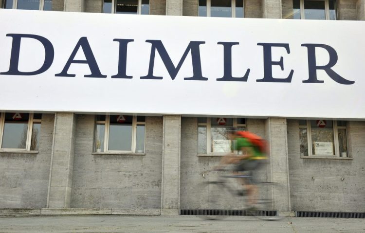 In this April 8, 2009 file photo, a cyclist passes a logo of German car company Daimler in Berlin. German automaker Daimler said Friday, Nov. 29, 2019 that it plans to cut at least 10,000 jobs worldwide by the end of 2022. 