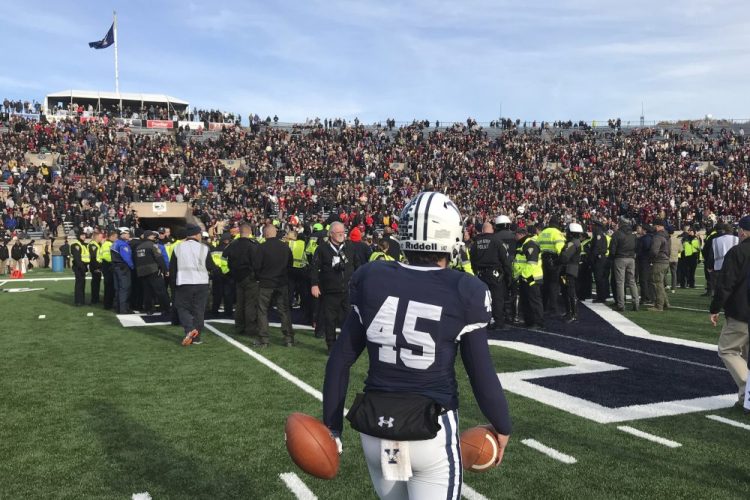Yale punter Jack Bosman watches as demonstrators stage a protest on the field at the Yale Bowl, disrupting the start of the second half of an NCAA college football game between Harvard and Yale, Saturday in in New Haven, Conn.